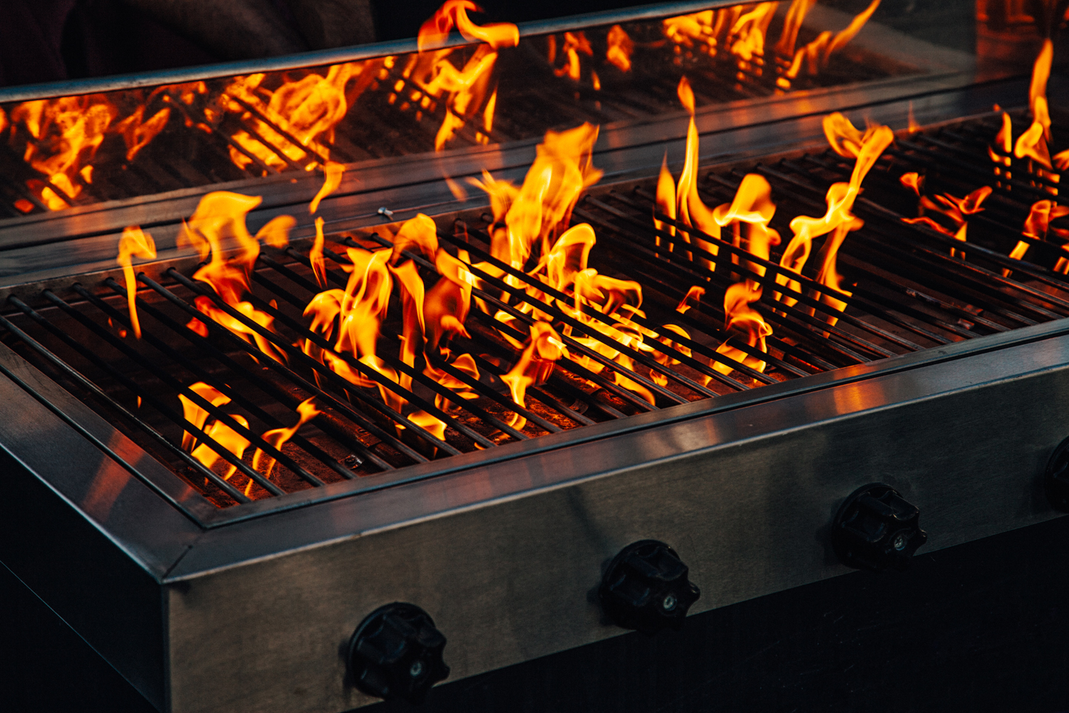 Hot Barbeque gas gril with bright yellow flames angburning coals. Working with music sound equalizer system.